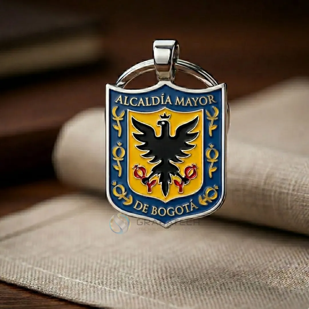 Llavero metálico en forma de escudo con águila negra sobre fondo amarillo y azul