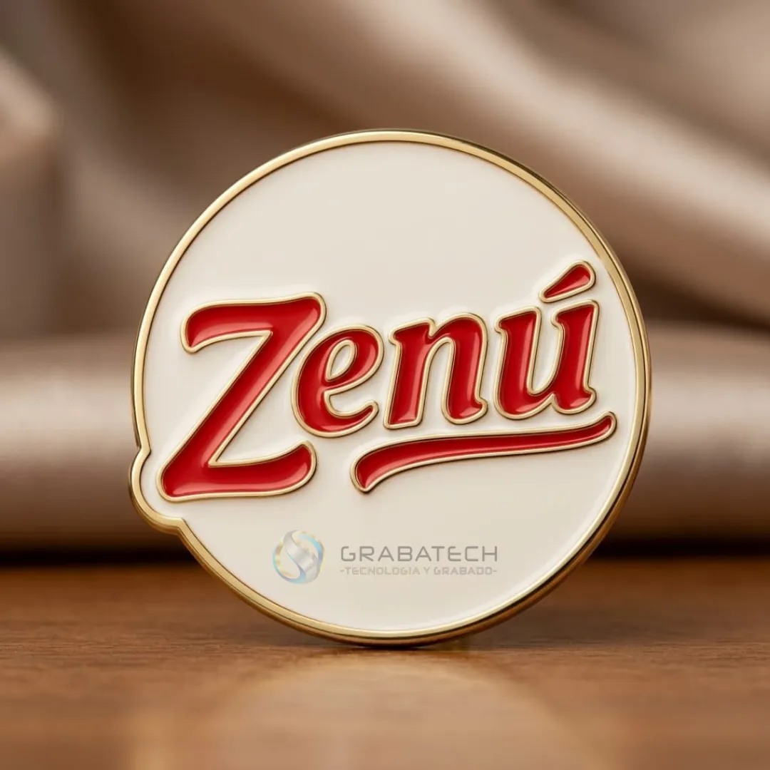 Pin circular en bronce con esmalte blanco, letras rojas y borde dorado