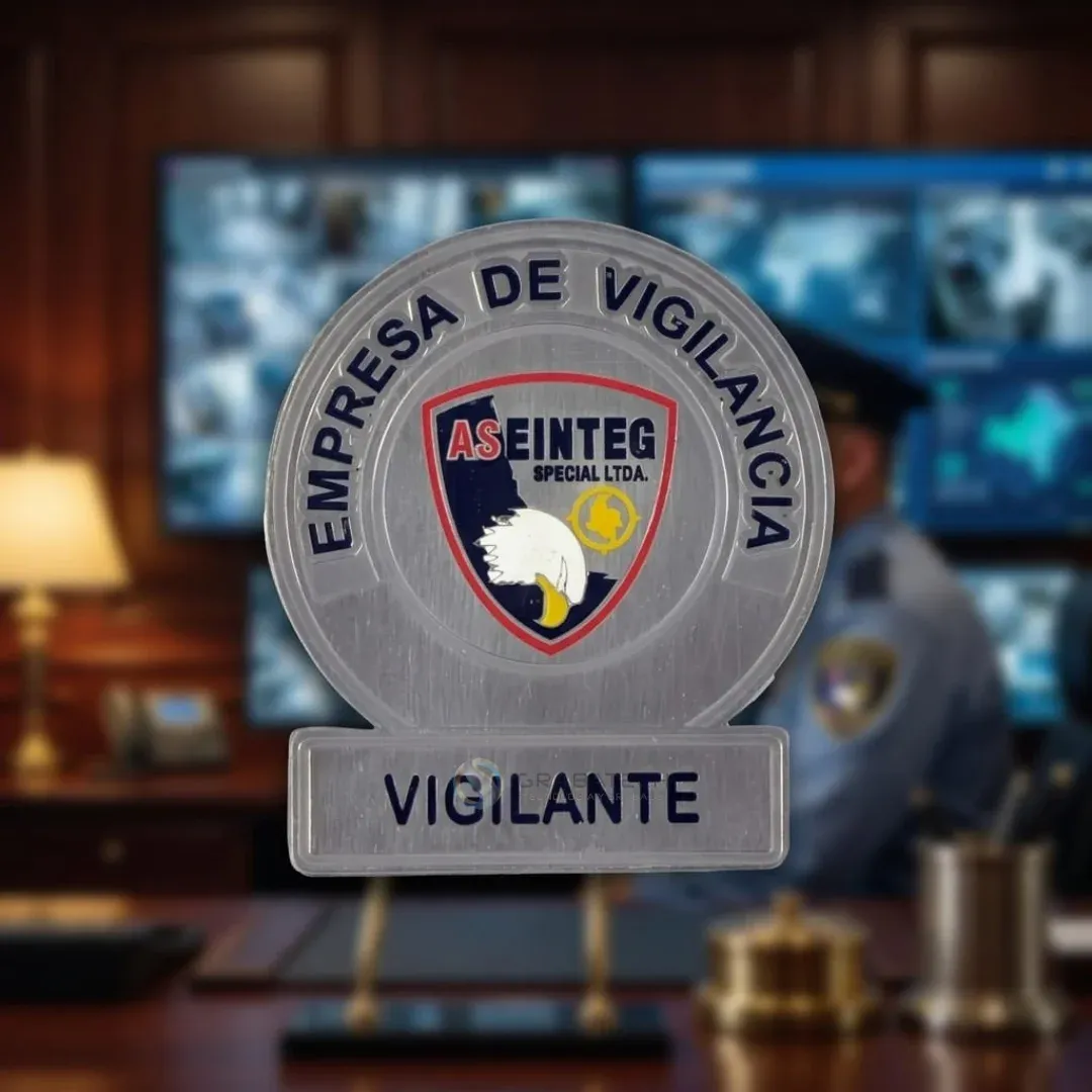 Placa de vigilancia metálica con escudo azul y rojo frente a monitores de seguridad